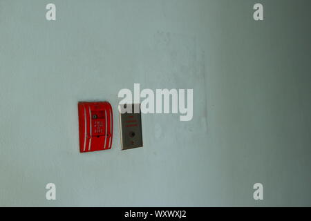 Libre de déclencheur manuel d'alarme incendie est installé sur le mur d'un bâtiment à côté de la prise téléphonique des pompiers, selective focus. Banque D'Images