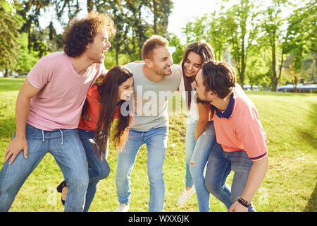 Un groupe d'amis qui rient hugging in a park Banque D'Images