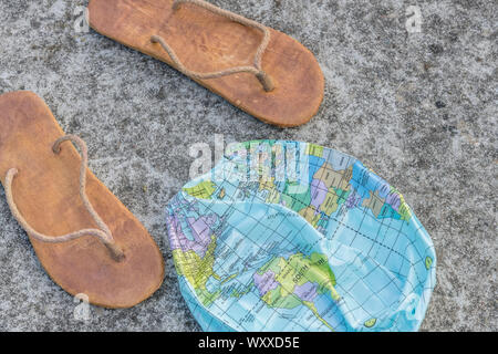 Hippy usés tongs & globe dégonflé sur surface en béton. Métaphore 250-504, télévision earthers, théories du complot, preuve de la terre plate, la pseudoscience Banque D'Images