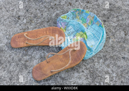 Hippy usés tongs & globe dégonflé sur surface en béton. Métaphore 250-504, télévision earthers, théories du complot, preuve de la terre plate, la pseudoscience Banque D'Images