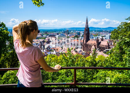 Allemagne, superbe jeune femme debout au-dessus de la ville de Freiburg im Breisgau vieille ville et cathédrale La cathédrale célèbre en été Banque D'Images