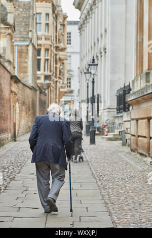 Un homme âgé avec un bâton de marche promenades le long passage de la Chambre du Sénat Sénat passé House, Université de Cambridge, en Angleterre. Banque D'Images