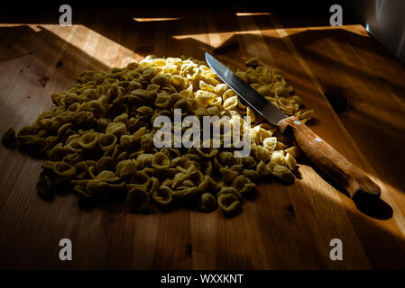 Orecchiette, semoule de blé, les pâtes Italiennes sur une table et un couteau. Banque D'Images