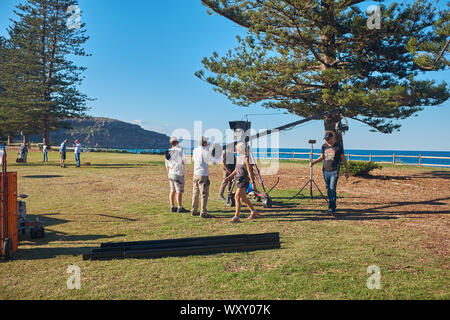 Avec une équipe de télévision caméra sur un boom ou flèche de la préparation d'une scène de film en plein air à domicile et à l'extérieur du programme de télévision au Palm Beach, New South Wales, Australie Banque D'Images