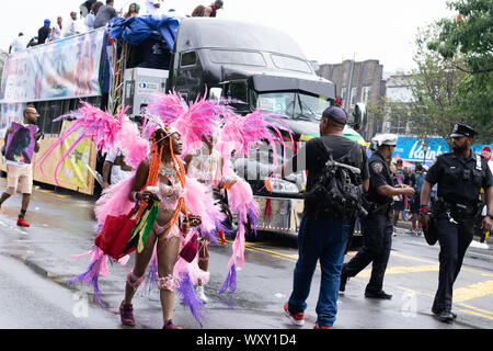 Tanzend zu schwarzenberg Musik laufen zwei Frauen mit rosafarbenem Kostüm und Federn auf der West Indian Day Parade à New York City un den Zuschauern vorbei Banque D'Images