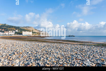 Une vue de la jetée de Llandudno et plage de galets. Le grand orme pointe est derrière et un ciel bleu est au-dessus. Banque D'Images