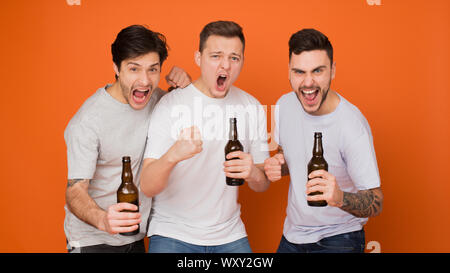 Les gars émotionnelle holding les bouteilles de bière, sur fond orange Banque D'Images