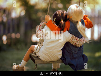 Deux petites filles se balançant ensemble sur tree swing. Banque D'Images