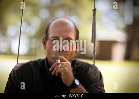 Close up of a young man smoking sur la balançoire dans le parc. Banque D'Images