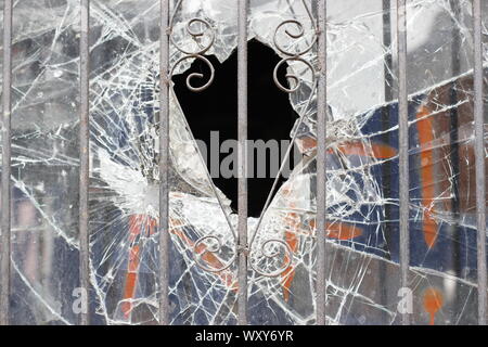 Résumé image montrant verre brisé et dans le trou d'une vitre cassée derrière un volet de sécurité métal grill Banque D'Images