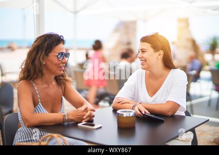 Belle Mère et fille assis à une terrasse de restaurant parlant et souriant Banque D'Images