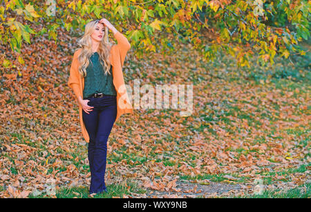 Femme à pied. La lumière au coucher du soleil Tenues décontractées confortable pour la fin de l'automne. Tenue confortable. Adorable petite fille blonde posing in outfit chaleureux et cosy de l'automne nature fond flou. Création pour agréable fin de semaine. Banque D'Images