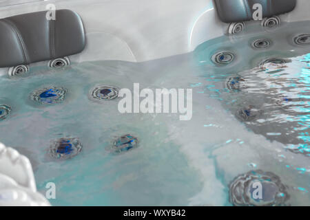 Vue sur la haute pression les buses de deux sièges de bain à remous baignoire bains à remous au spa avec appui-tête et la lumière colorée Banque D'Images