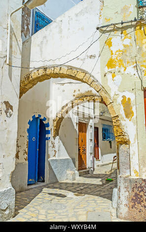 Promenade à travers la vieille passe en arc en mauvais état de la rue Medina arabe avec l'effritement du plâtre et de la peinture sur les murs, Bizerte, Tunisie Banque D'Images