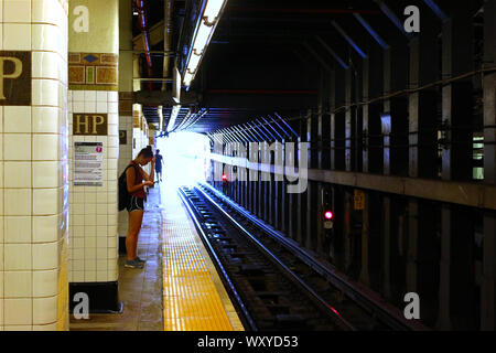 Jeune femme entrant attend 7 train sur Manhattan-bound Hunters Point la station de métro Avenue plate-forme. Queens le 22 juillet 2019 à New York, USA. (Phot Banque D'Images
