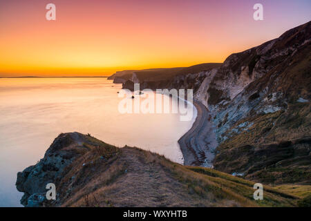 Dungy Head, Lulworth Ouest, Dorset, UK. 18 septembre 2019. Météo britannique. Ciel clair au coucher du soleil alors que le ciel devient orange vif à Dungy Head dans l'ouest de la crique de Lulworth sur la côte jurassique du Dorset en vue le long des falaises vers Durdle Door, chauves-souris et tête de Nothe blanc. Crédit photo : Graham Hunt/Alamy Live News Banque D'Images