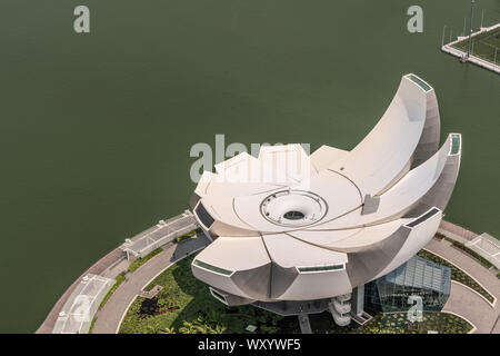 Singapour - Mars 21, 2019 : coup de toit des sables bitumineux. Birds Eye View sur circulaire blanc lotus de shell comme musée ArtScience. Marina verdâtre de l'eau. Banque D'Images