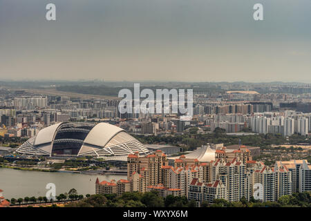 Singapour - Mars 21, 2019 : coup de toit des sables bitumineux. Birds Eye View of National Stadium avec toit ouvert et des dizaines de gratte-ciel autour, y compris red r Banque D'Images