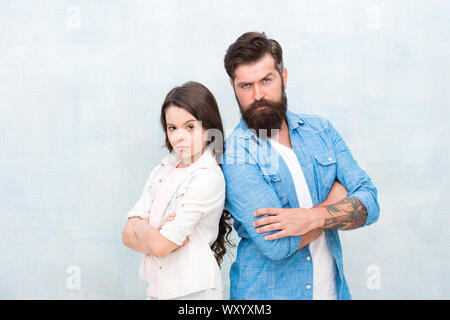 Des relations de confiance. Petite fille et son père en gardant les bras croisés sur fond gris. Homme barbu et petit enfant qui entretient des relations amicales. Les relations familiales et les obligations. Relations extérieures et de la relation. Banque D'Images