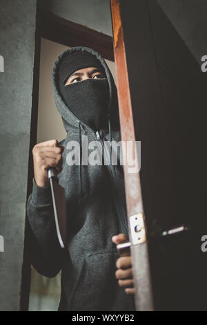 Le voleur est titulaire d'un couteau pour ouvrir la porte de la maison pour vol qualifié. Banque D'Images