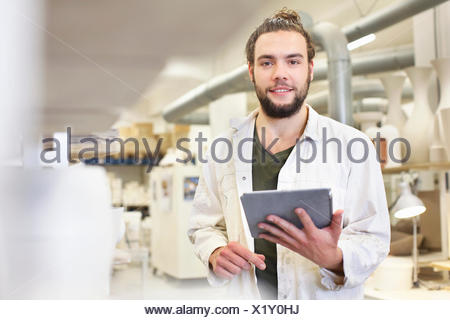 Potter mâle using digital tablet in atelier de céramique