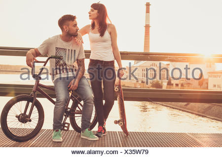 Jeune couple avec Skateboard and BMX location reposant sur bridge