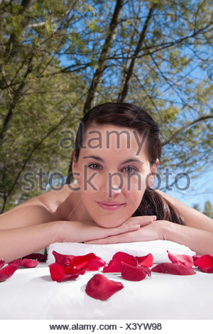 Portrait d'une femme allongée sur une table de massage avec des pétales de rose