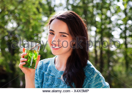 Portrait of young woman in garden avec soft drink