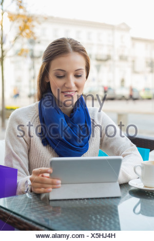 Young woman using tablet PC at sidewalk cafe