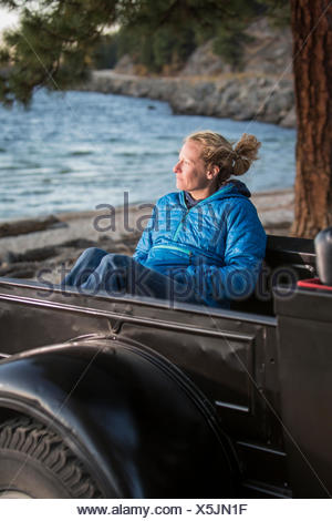 Femme assise en regardant le coucher du soleil, camion rénové Lac Payette, McCall, New York, USA