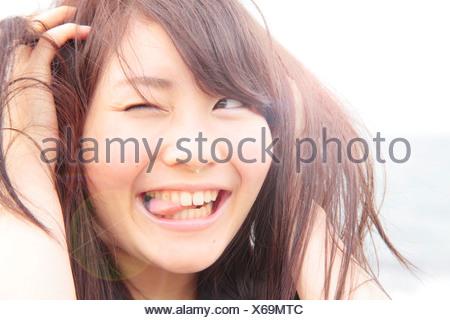 Portrait de jeune femme, les mains dans les cheveux, sticking tongue out