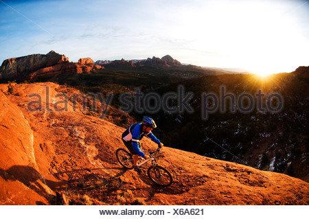 Un homme d'âge moyen chevauche son vtt à travers le red rock country autour de Sedona, Az au coucher du soleil.