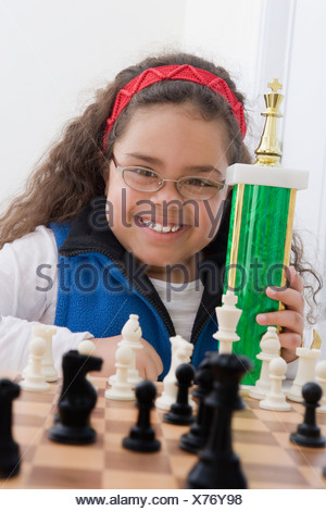 Portrait of young girl holding chess trophy