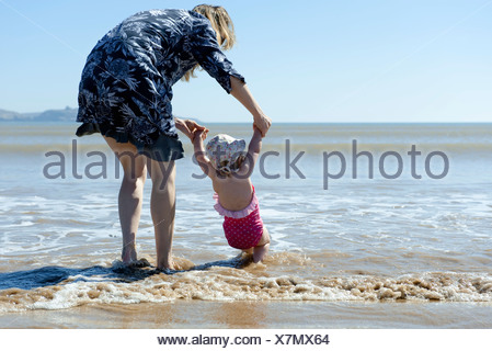 Mère et bébé fille marcher dans de surf à la plage, vue arrière