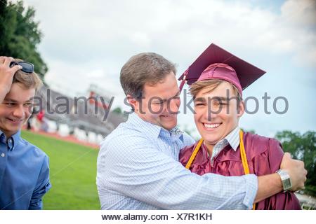 Jeune homme d'être embrassé par le père à la cérémonie de remise des diplômes