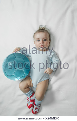 Un Petit Garcon Portant Des Chaussures De Foot Bebe Couche A Cote D Un Ballon De Foot Photo Stock Alamy