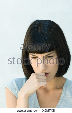 Woman biting pouce et regardant vers le bas, la tête et épaules, portrait