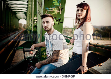 Jeune couple avec Skateboard and BMX bicycle outdoors