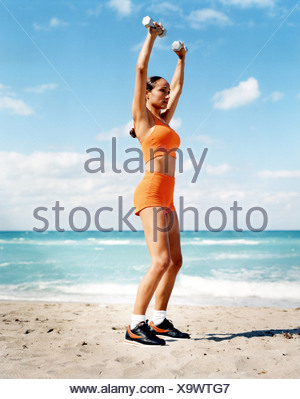 Femme brune, cheveux tressés portant un gilet orange rognée, orange shorts, chaussettes blanches