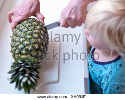 Boy watching woman slicing pineapple