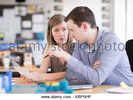 Young man and woman working on laptop in creative office