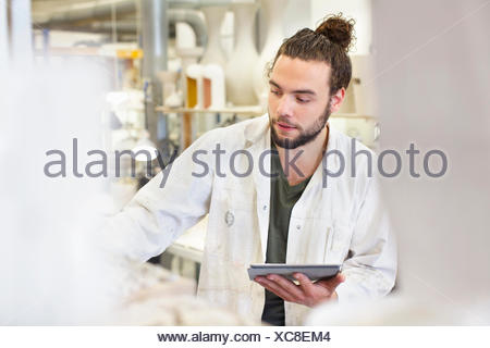 Potter mâle using digital tablet in atelier de céramique