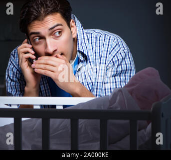 La felice papà alla ricerca dopo il neonato di notte Foto Stock