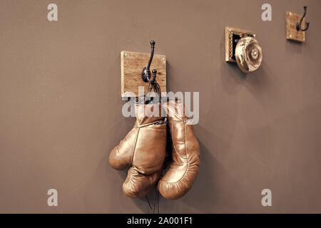 Scuola di inscatolamento. Il combattimento finale. Vintage guantoni da boxe da appendere alla parete gancio dello sfondo. I guantoni e suoneria. Carriera di inscatolamento famoso atleta. Museo di box sport. Nella casella mostra gli attributi retrò. Foto Stock