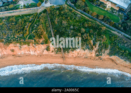 Guardando verso il basso a lungo le scale di legno che conducono a una appartata spiaggia dell'oceano - vista aerea Foto Stock