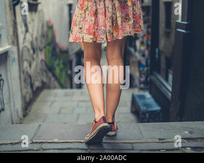 Le gambe di una giovane donna che cammina giù per le scale al di fuori di una città Foto Stock