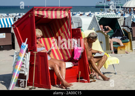 Anziani, la gente tedesca vacanza su una spiaggia del Mar Baltico Vacanze estive Germania Warnemunde strandkorb Foto Stock