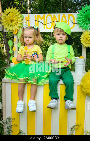 Piccolo Ragazzo e ragazza seduta su lemonade stand nel parco nel giorno di estate Foto Stock