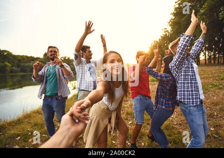 Gli amici hanno divertimento che corre lungo il lago su un picnic. Foto Stock