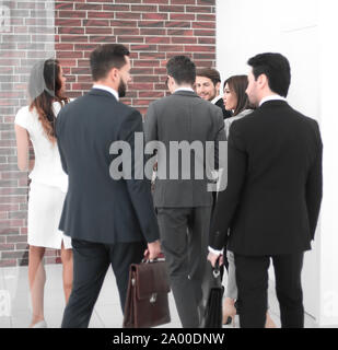Un gruppo di persone di affari di parlare, in piedi nella lobby del centro business. Foto Stock